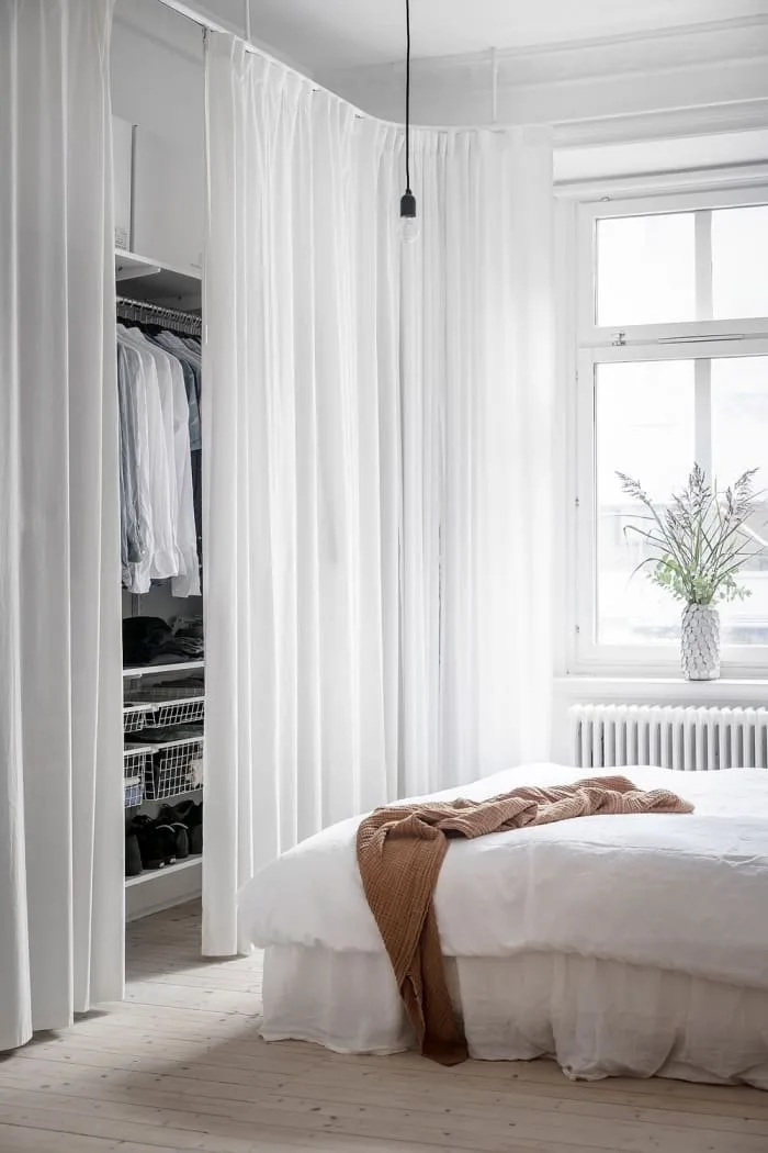 aménagement-dressing-avec-rideaux-chambre-à-coucher-blanche-dressing-ouvert-derrière-rideau-blanc-parquet-bois-clair